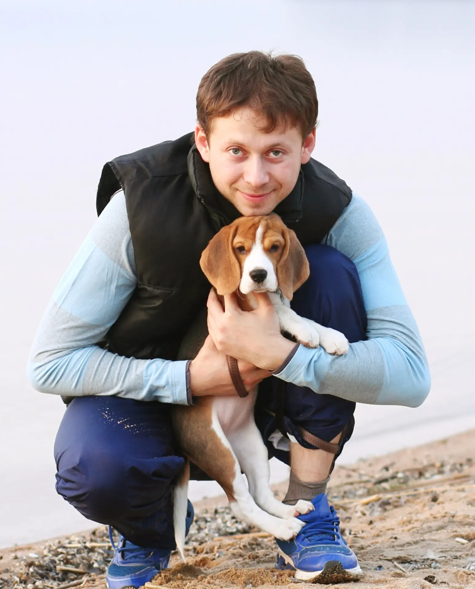 Opiekun przytulający szczeniaka beagle na plaży